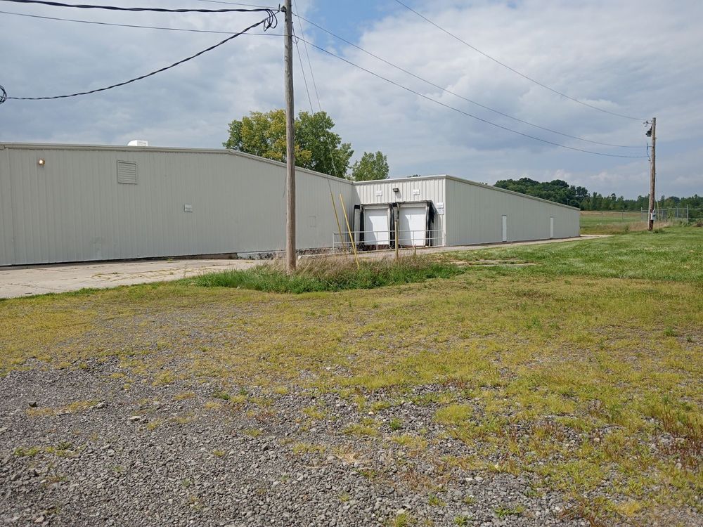 A large building is sitting in the middle of a grassy field.
