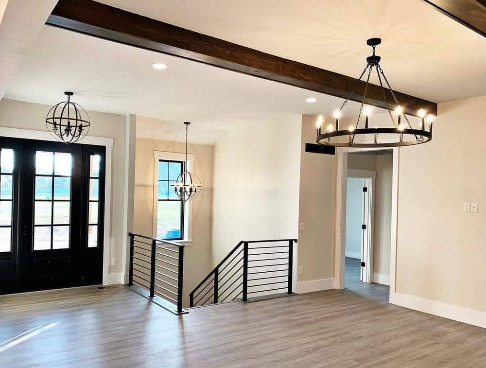 An empty room with a staircase and a chandelier hanging from the ceiling.