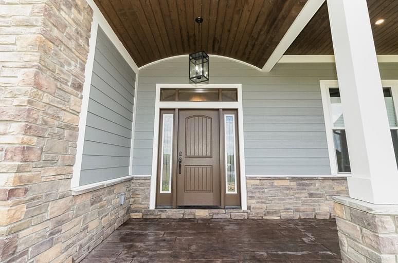 The front door of a house with a porch and a lantern hanging from the ceiling.