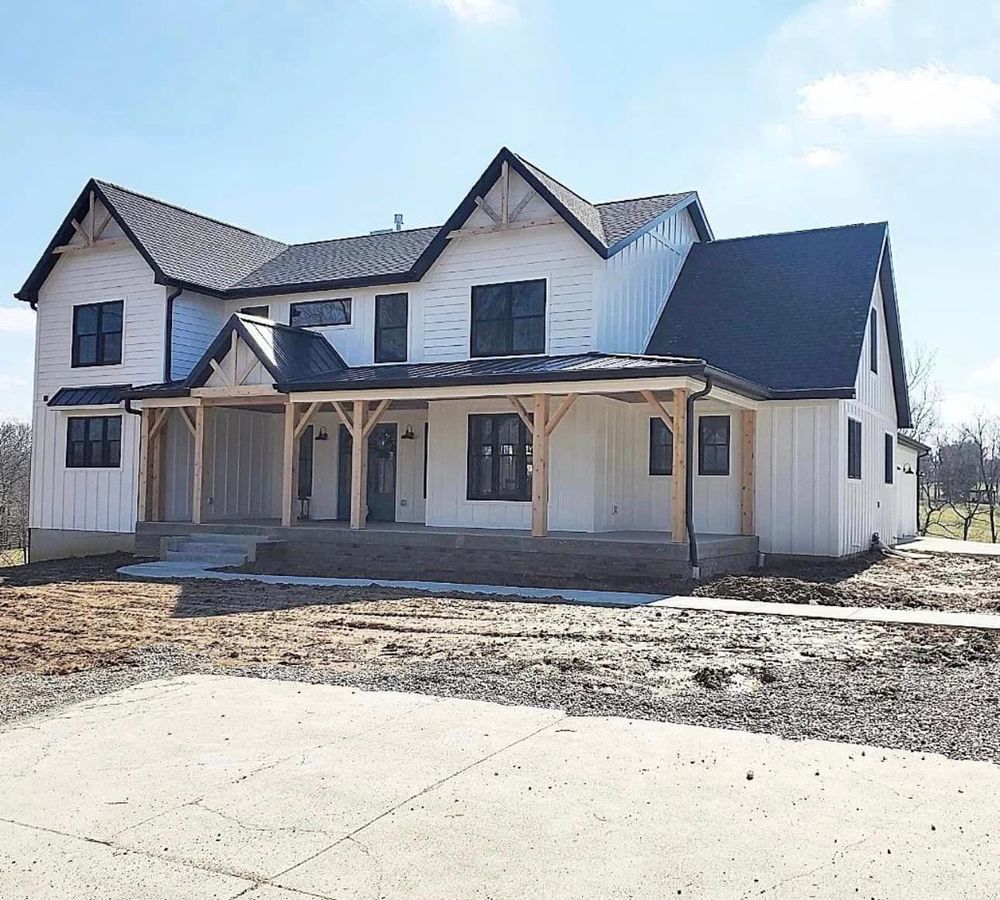 A large white house with a black roof and a porch.