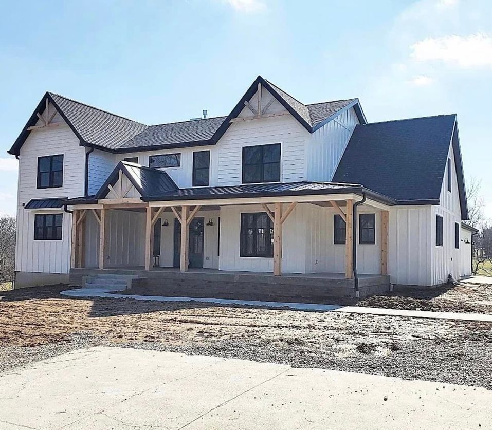 A large white house with a black roof and a porch.