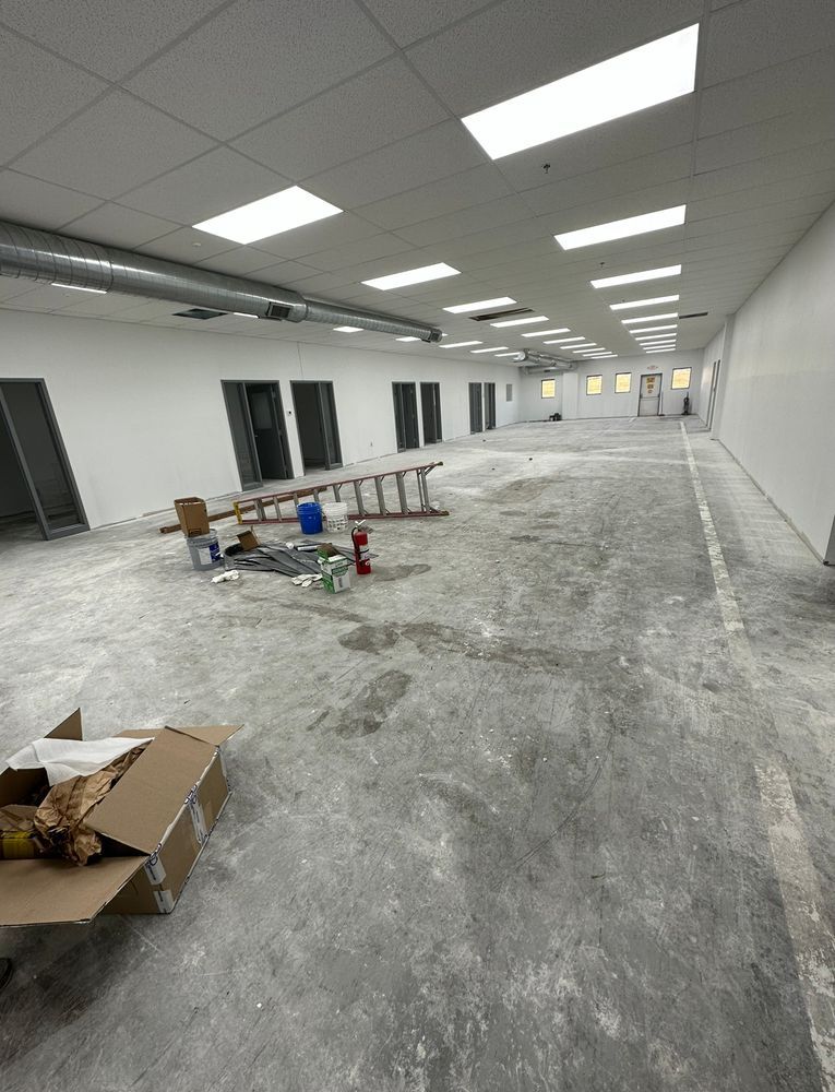A large empty room with white walls and a concrete floor.