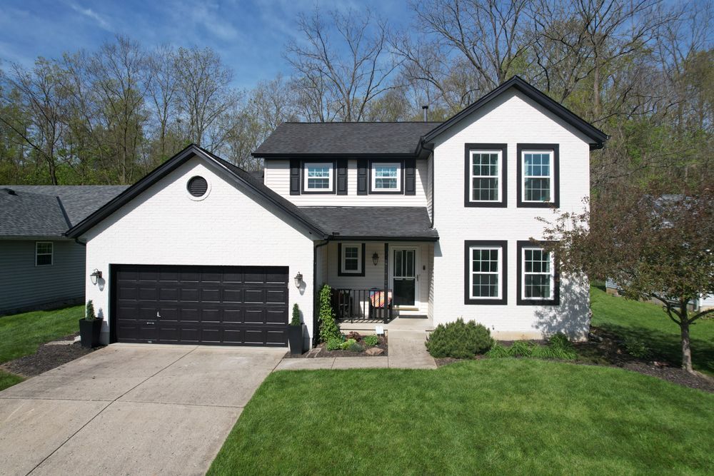 A white house with black trim and a black garage door.