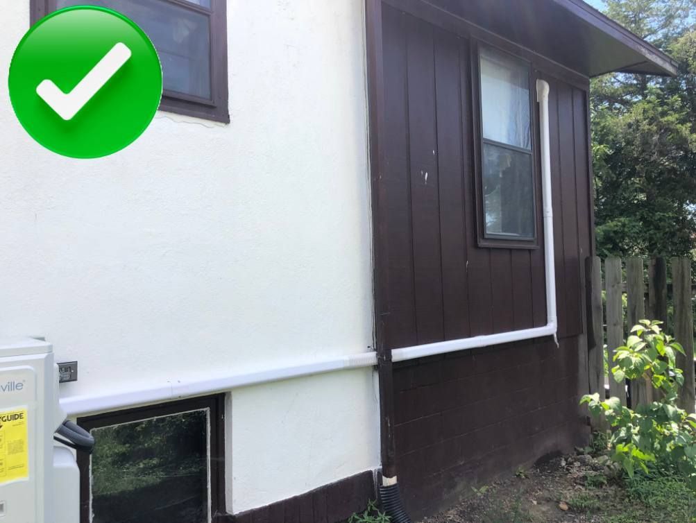 Exterior of a house with white and brown siding, a green checkmark, and a window.