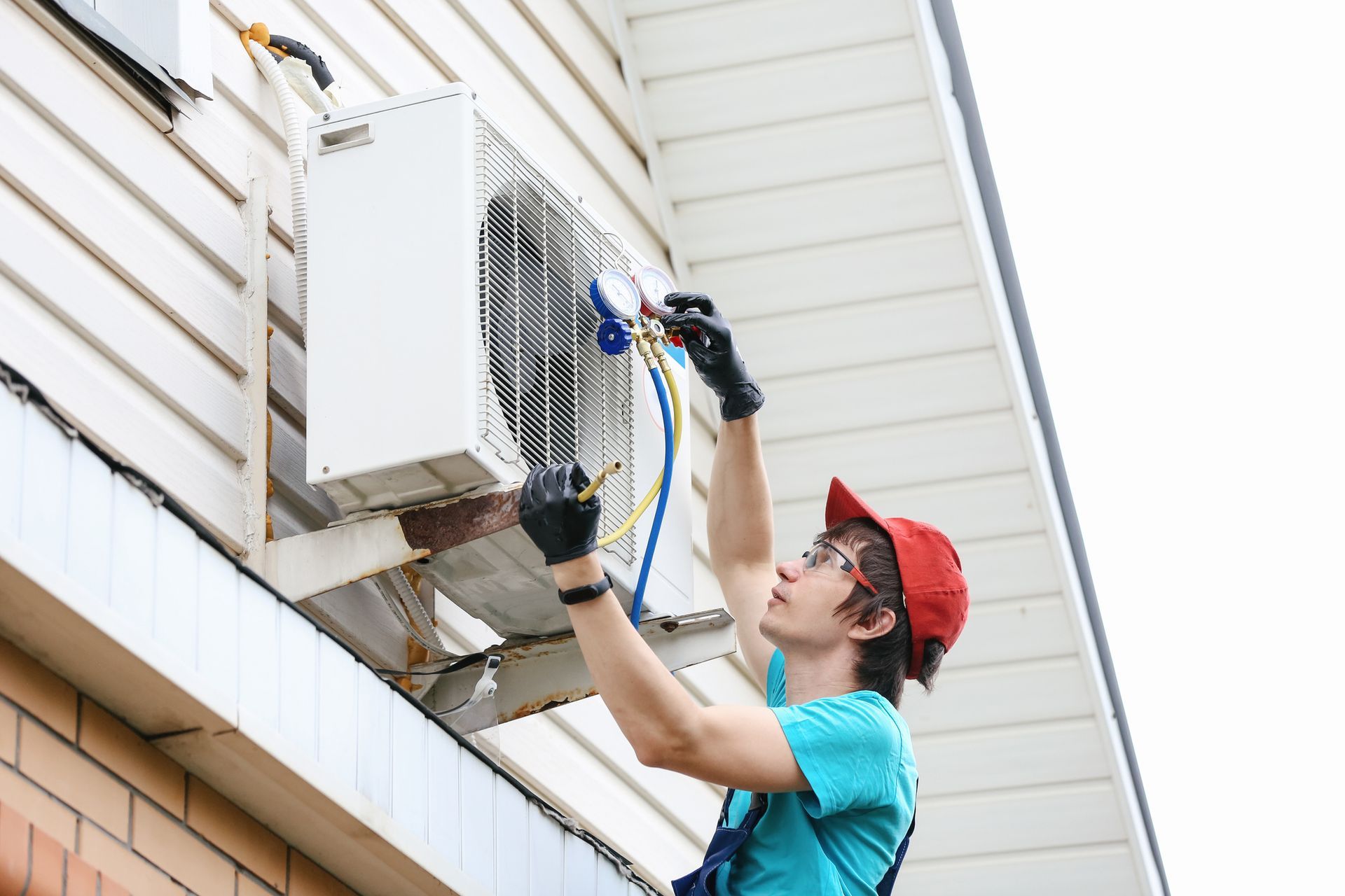 A man is working on an air conditioner on the side of a building.