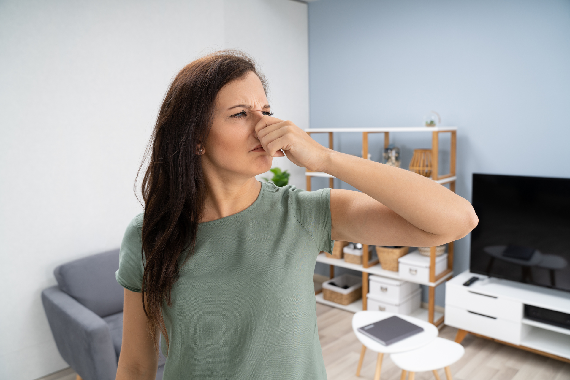 A woman is covering her nose with her hand in a living room.