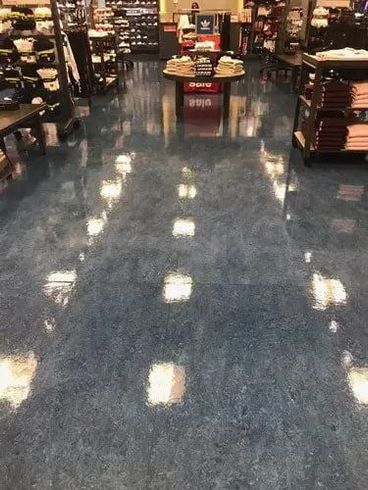 A shiny blue floor in a store aisle, reflecting overhead lights and merchandise displays.