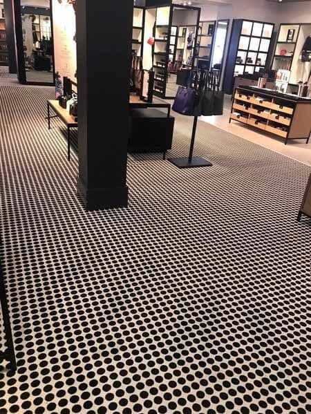 Black and white patterned floor in a store with displays, a support column, and bags.