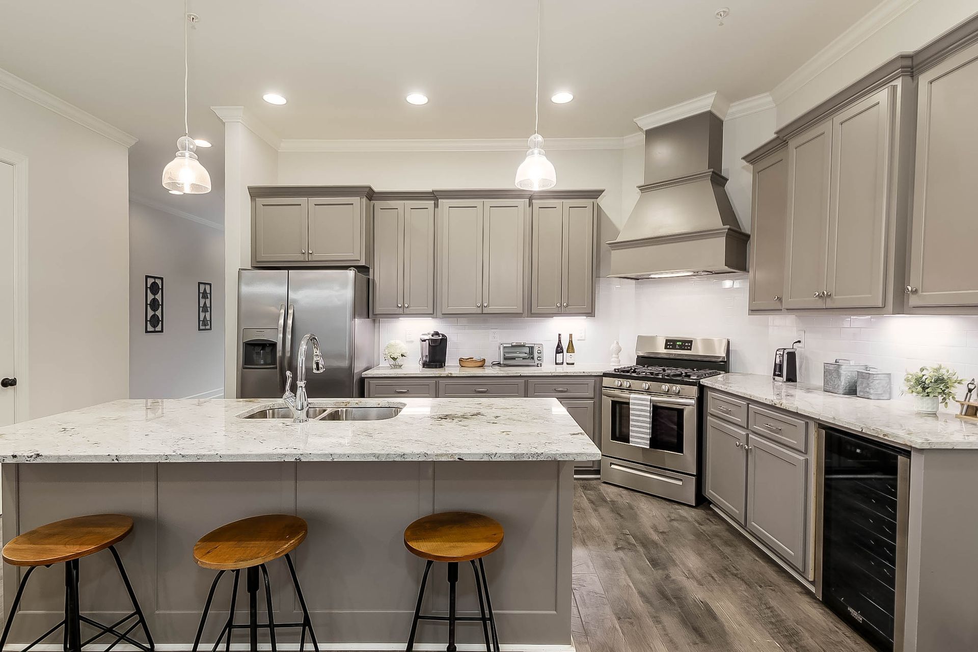 Modern kitchen with gray cabinets, stainless steel appliances, and a granite island with stools.