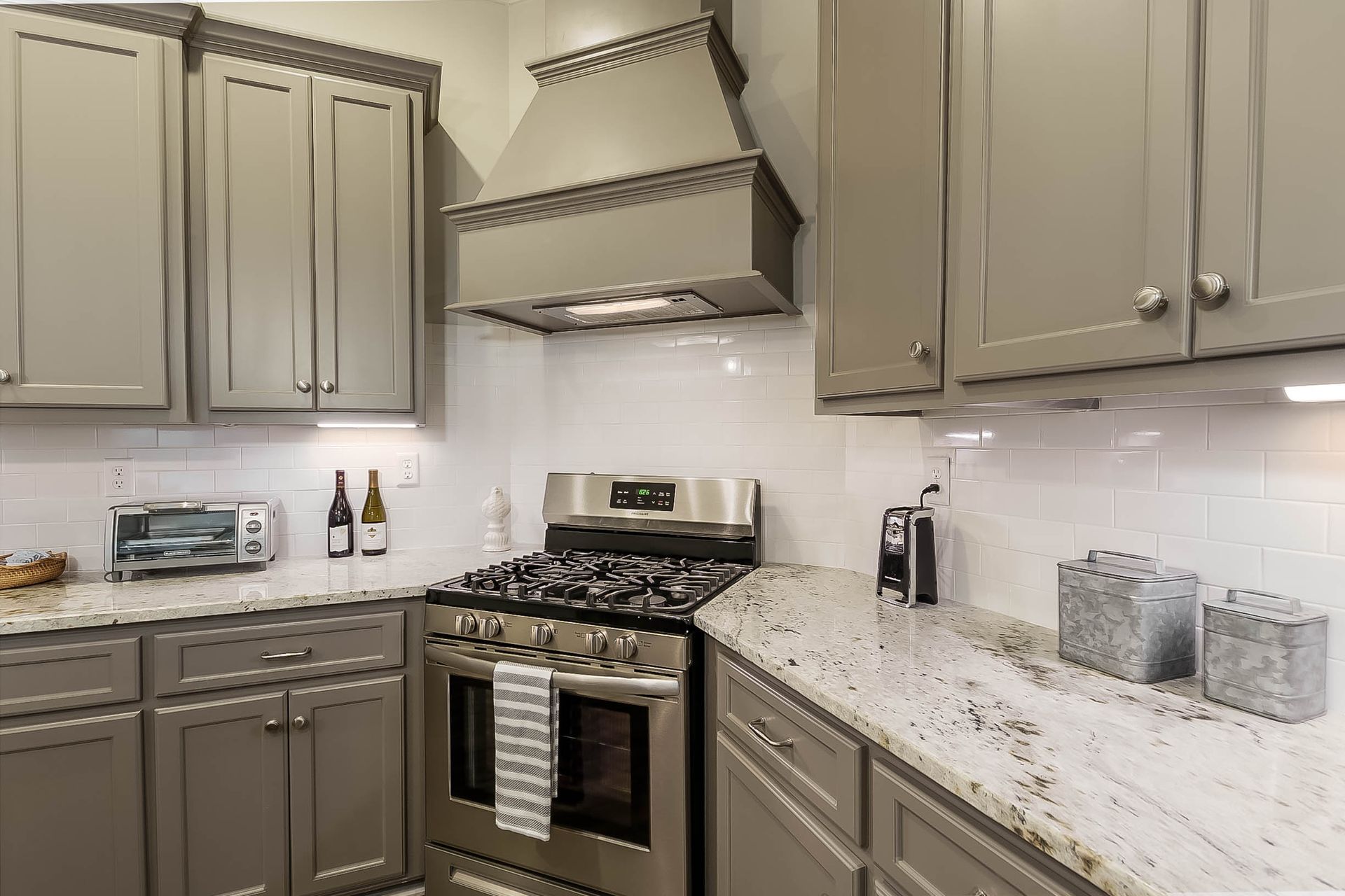 Gray kitchen with stainless steel appliances, white tile backsplash, and granite countertops.