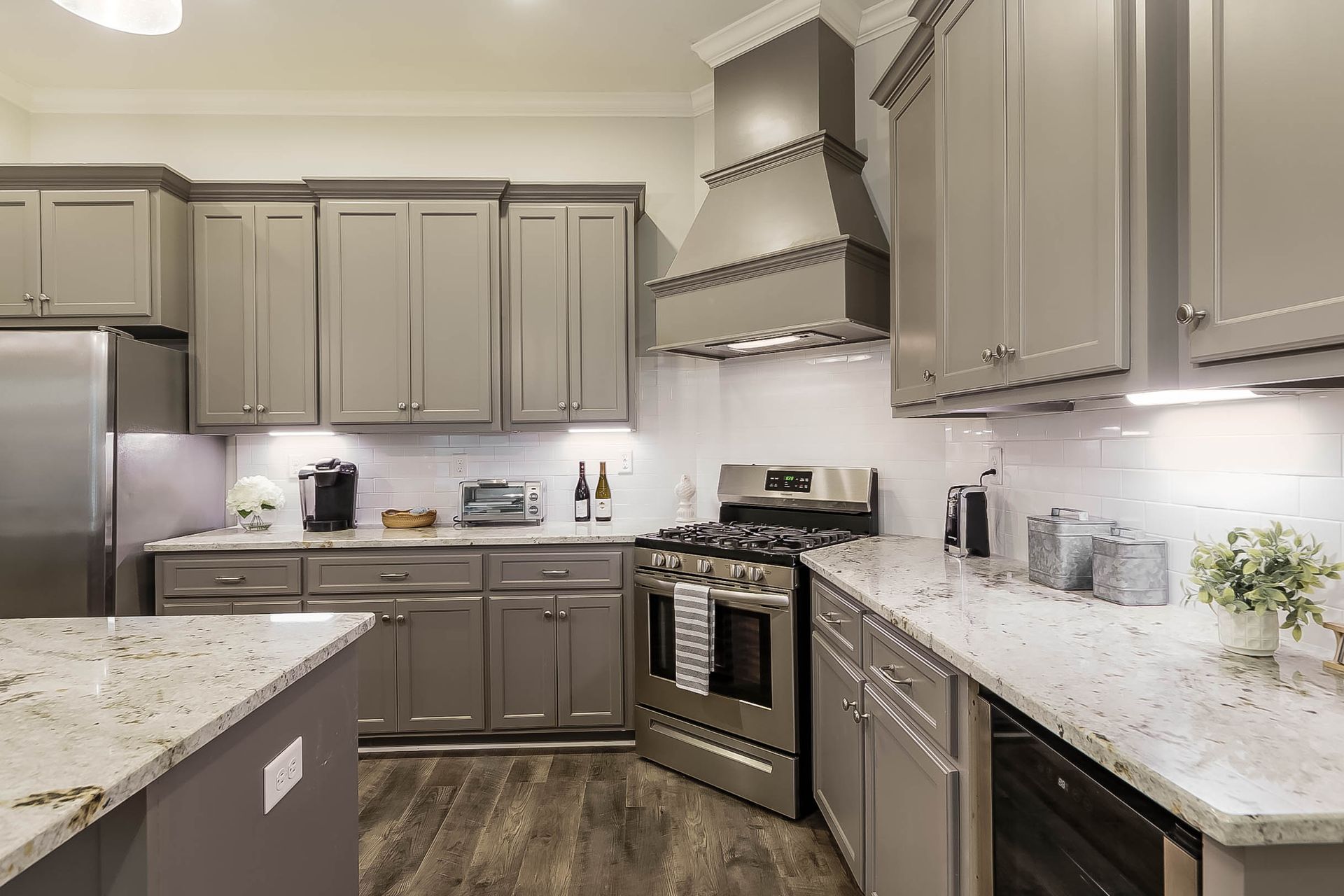 Gray kitchen with stainless steel appliances, granite countertops, and light tile backsplash.