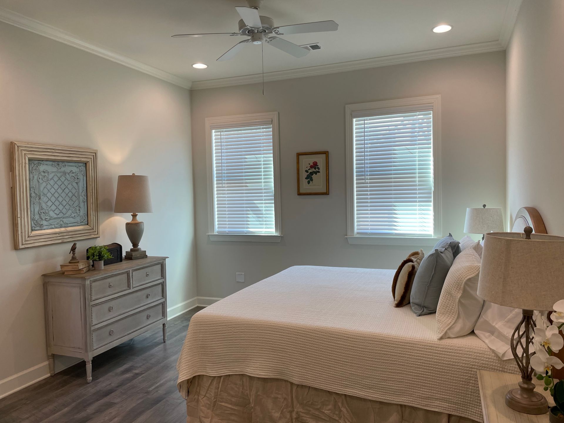 Bedroom with bed, dresser, windows, and neutral-colored walls.