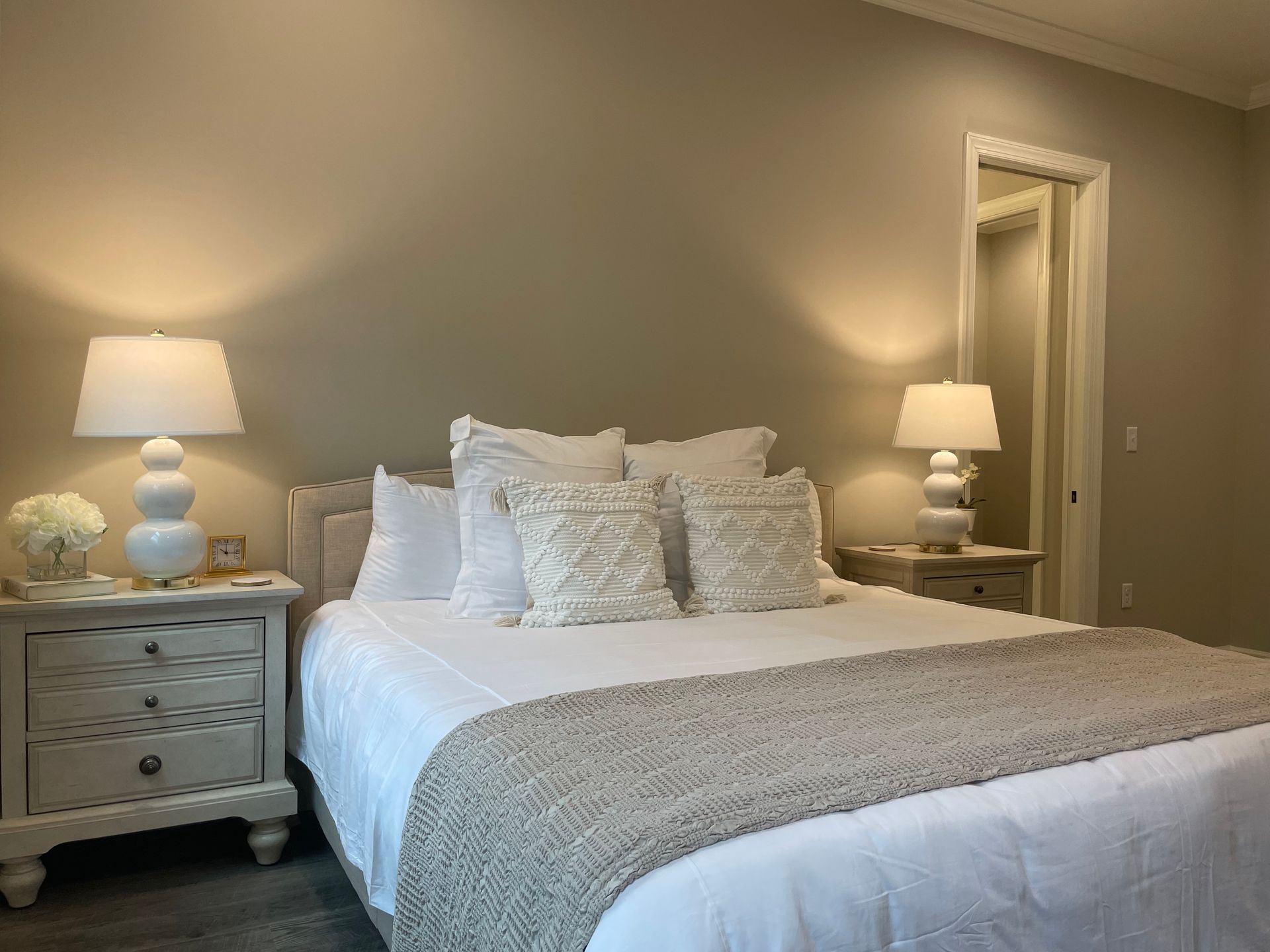 Bedroom with bed, nightstands, lamps, and decorative pillows. Neutral color scheme.