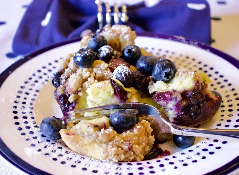 A plate of food with blueberries and a fork on it.