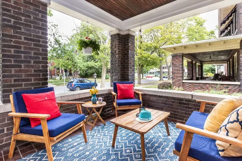 A porch with chairs , a table and a rug.