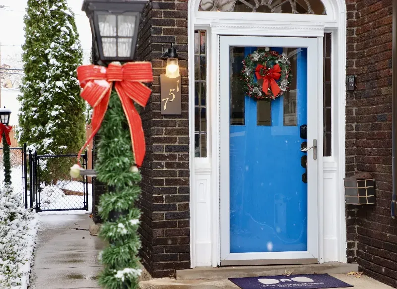 A blue door is decorated for christmas with a red bow