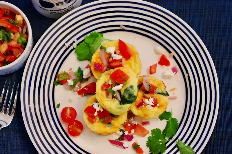 A plate of food with tomatoes and cheese on a table with a fork.