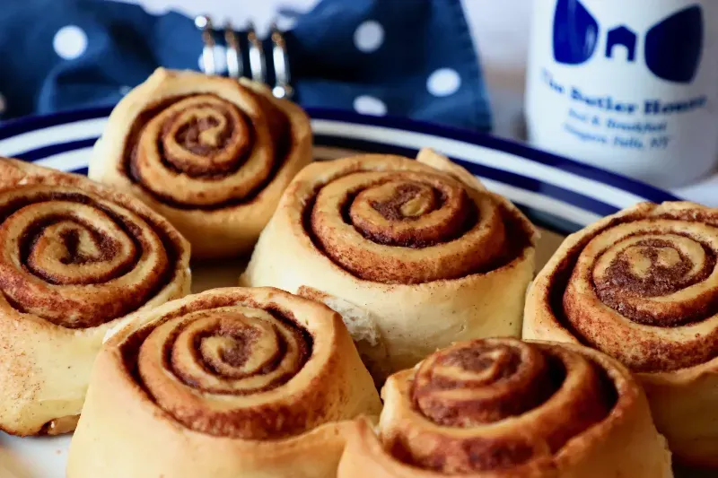 A plate of cinnamon rolls with a cup of milk in the background.