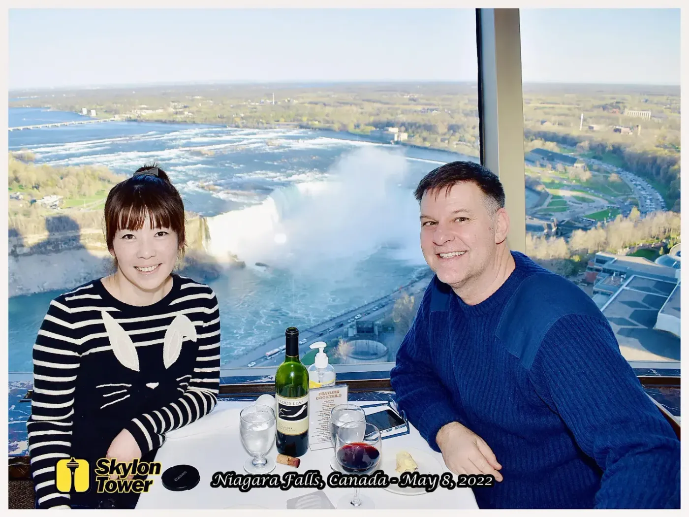 A man and a woman are sitting at a table with a view of niagara falls.
