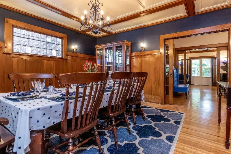 A dining room with a table and chairs and a blue rug.