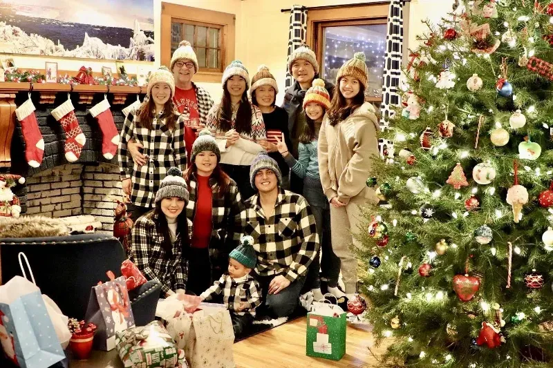 A group of people are posing for a picture in front of a christmas tree.