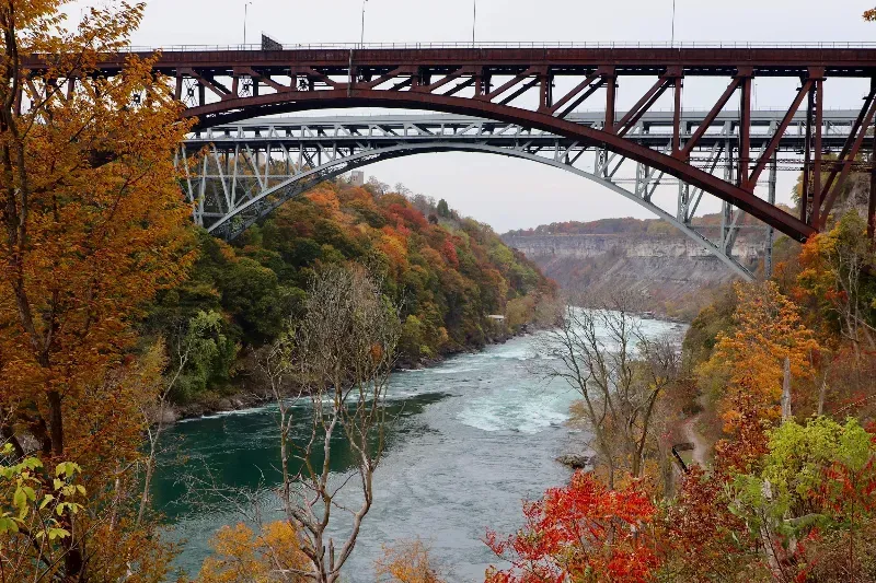 A bridge over a river surrounded by trees in autumn.