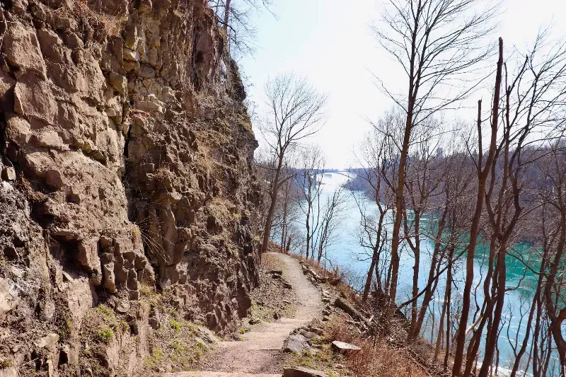 A path going down a cliff next to a body of water.