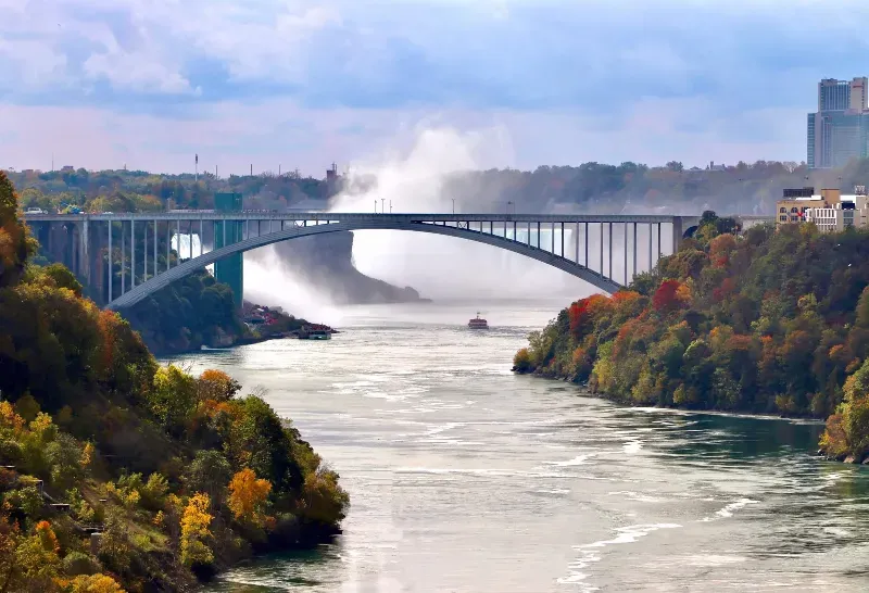 A bridge over a river with a waterfall in the background.