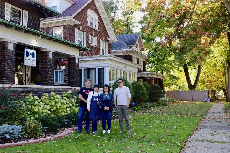 A group of people are standing in front of a large house.