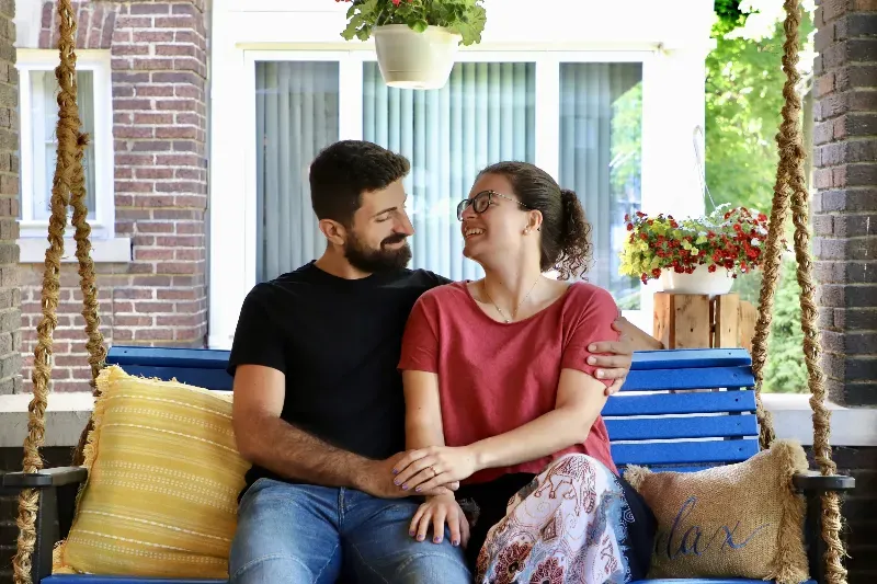 A man and a woman are sitting on a porch swing.