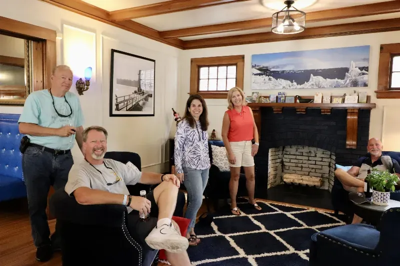 A group of people are standing around a fireplace in a living room.