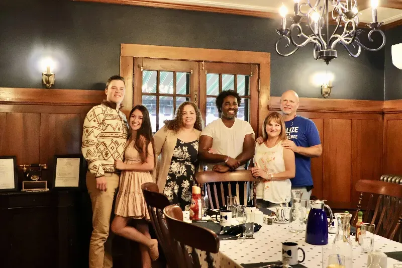 A group of people are posing for a picture in a dining room.