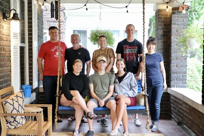 A group of people are posing for a picture on a porch swing.