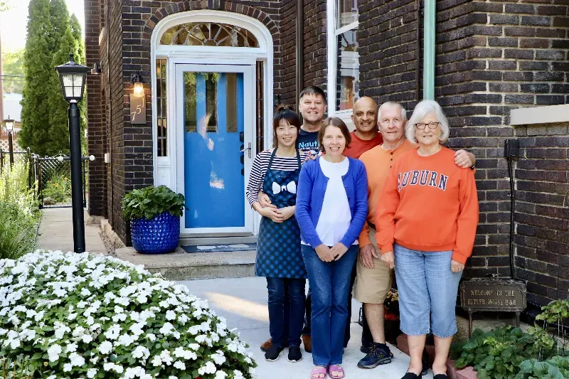 A group of people are posing for a picture in front of a house.