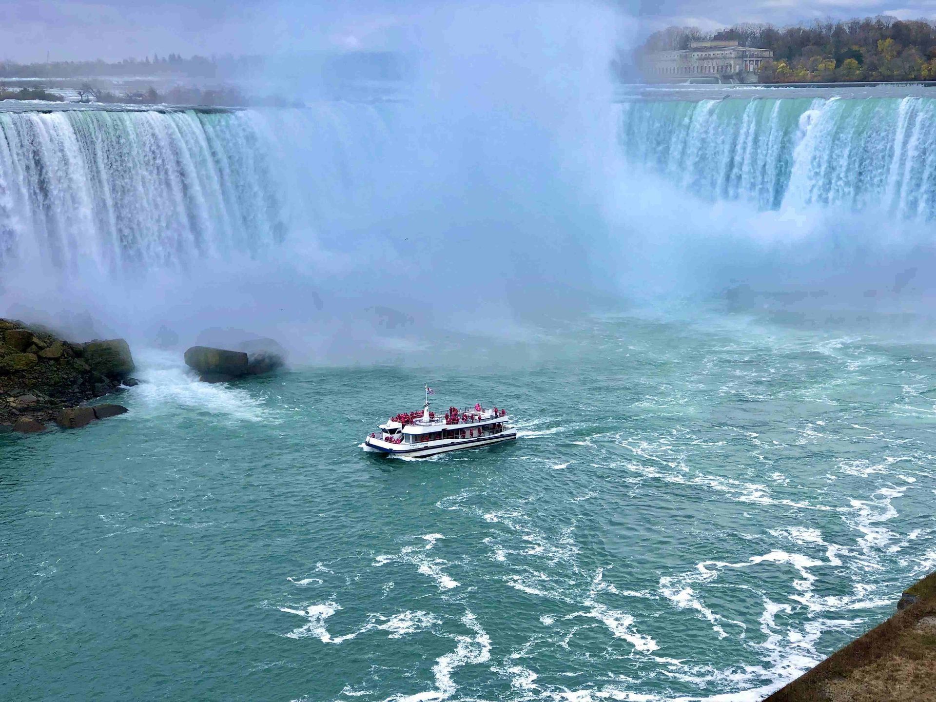 A boat is going down a river near a waterfall.