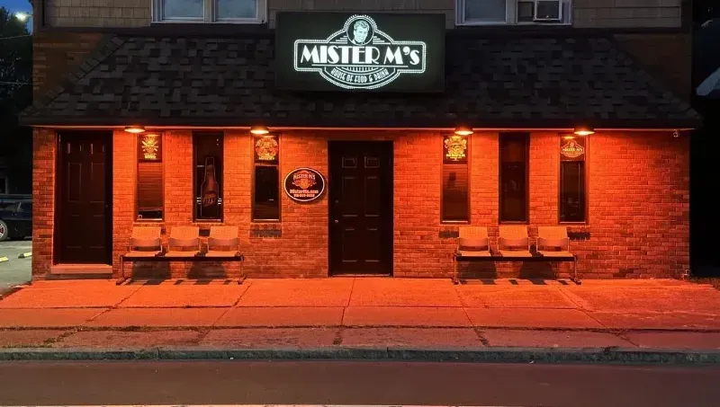 A brick building with a sign that says mister m 's is lit up at night.