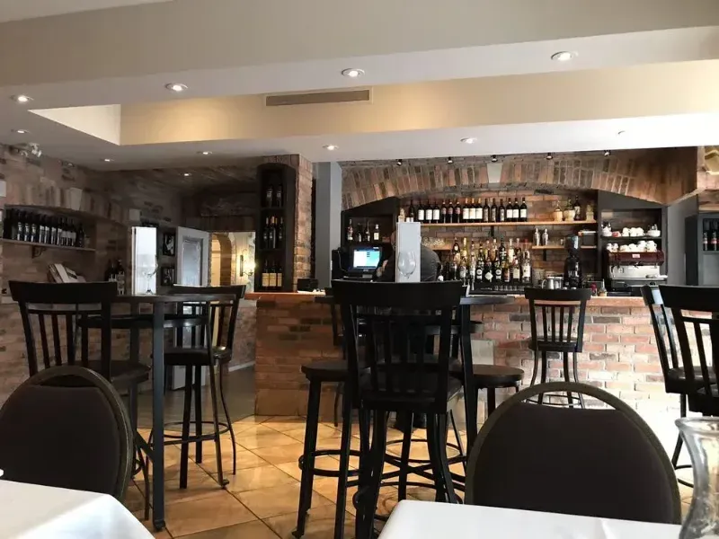 A restaurant with tables and chairs and a bar.