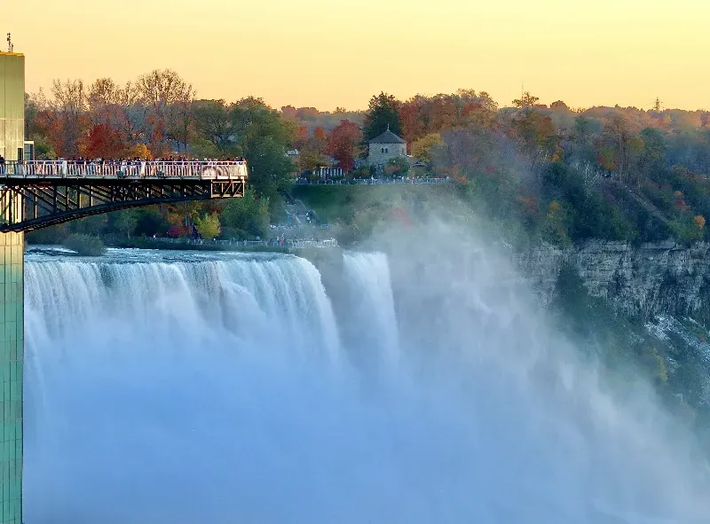A group of people are standing on a bridge over a waterfall.