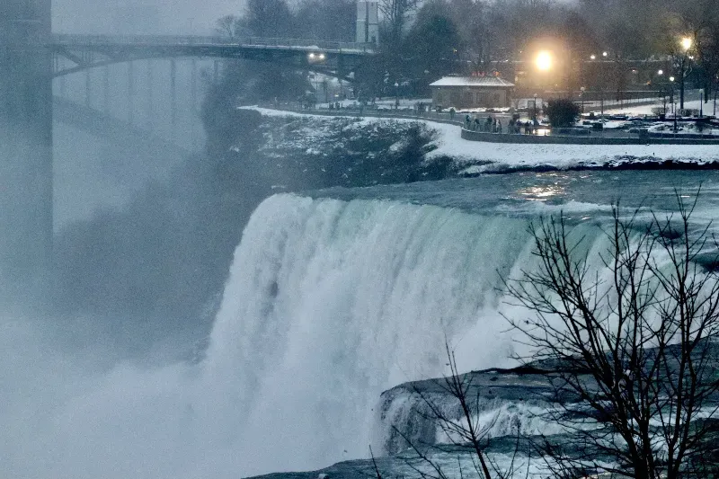 A waterfall in the snow with a bridge in the background