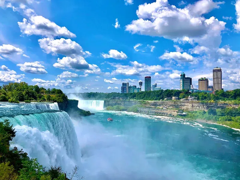 Niagara falls is a waterfall in canada with a city in the background.
