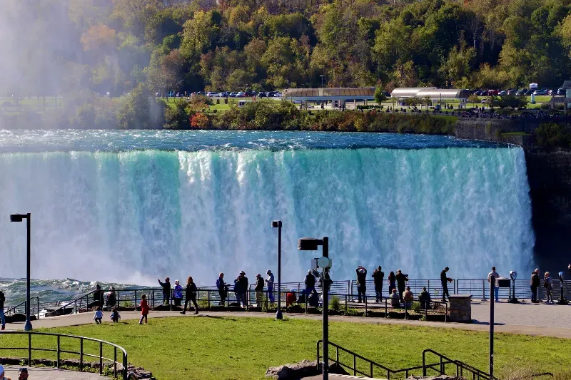 A group of people are standing in front of a waterfall.