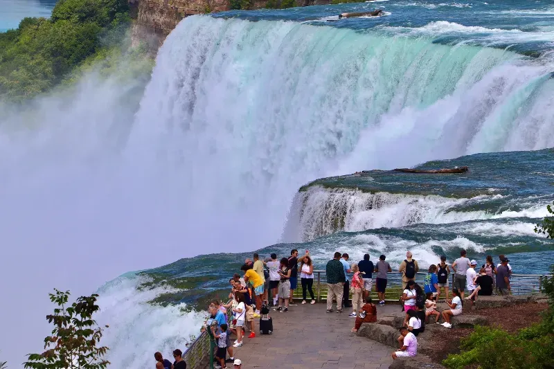 A group of people are standing on the edge of a waterfall.