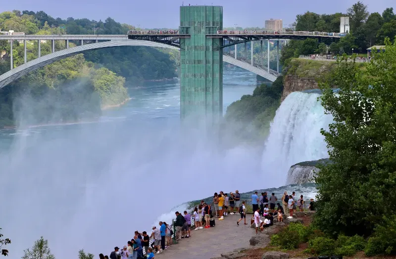 A group of people are standing on the edge of a waterfall.