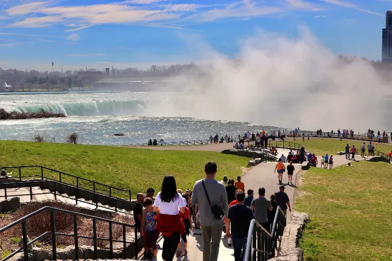 A group of people are walking down stairs in front of a waterfall.