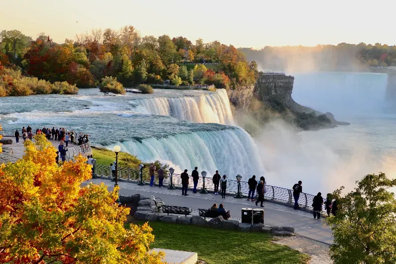 A group of people are standing on a fence looking at a waterfall.