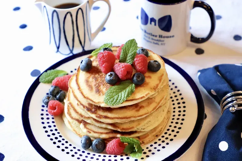 A plate of pancakes with raspberries and blueberries on top