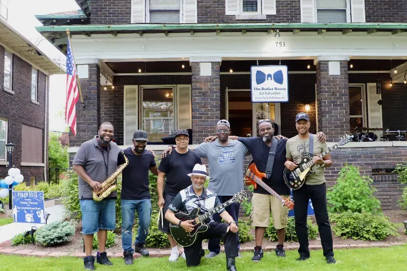A group of men are posing for a picture in front of a house.