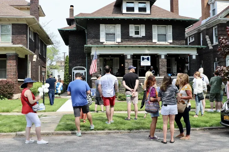 A group of people are standing in front of a house.