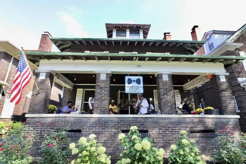 A group of people are sitting on a porch of a brick house.