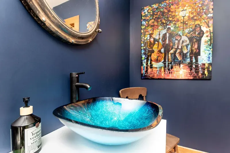 A bathroom with a sink , mirror and painting on the wall.